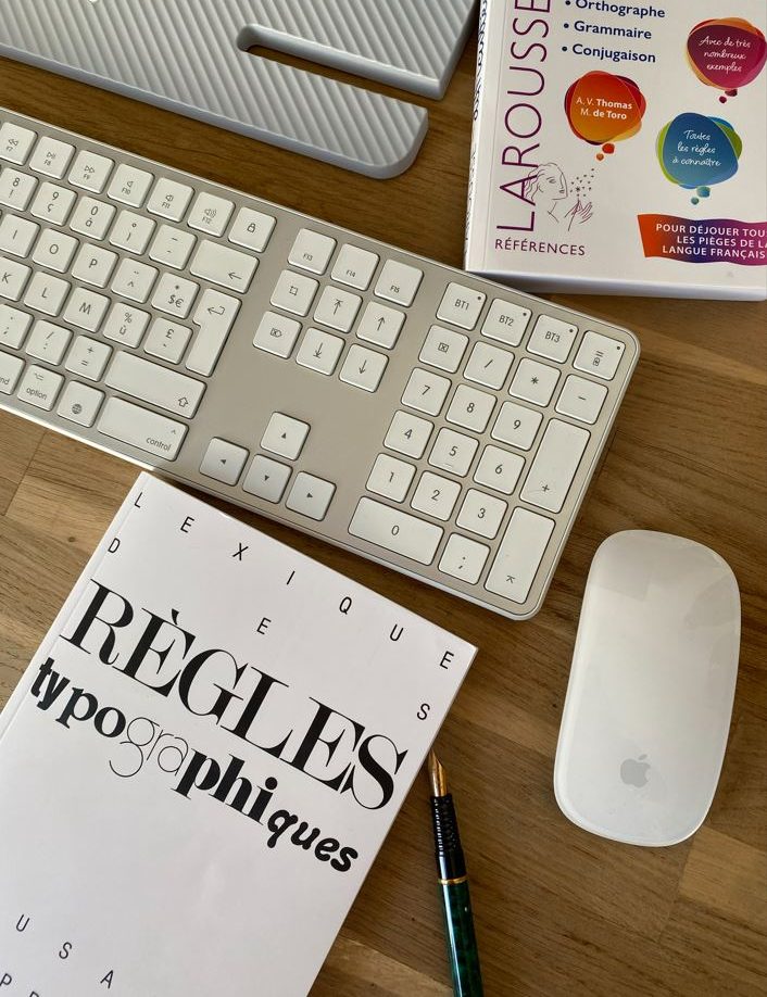 vue du plateau d’un bureau avec clavier, souris, stylo et livres de correction